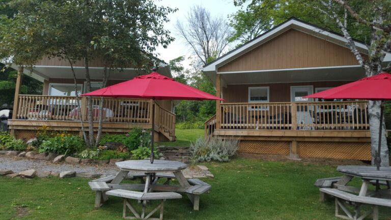 Lakefront cottages with red umbrellas at Ogopogo Resort, cottage rental rates in Minden